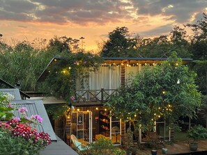 A rustic cabin with a balcony, surrounded by lush greenery and string lights. - Hometa Homestay (Bao Loc)
