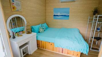 Ein Schlafzimmer mit einer Holzwand, einem Bett mit blauer Decke, einer weißen Kommode, einem Spiegel und einem Regal mit Pflanzen.