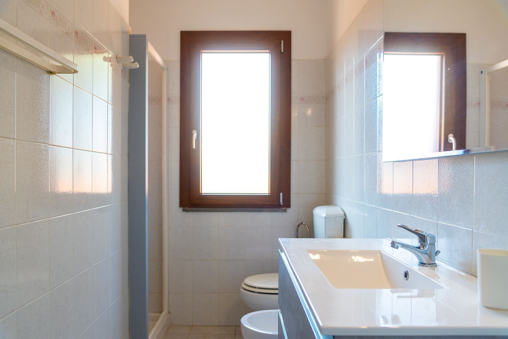 A bathroom with a large window, a sink, and a toilet.