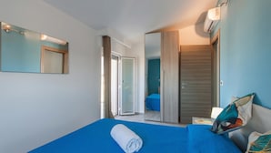 A hotel room with a bed, a mirror, a wardrobe, and a sliding door leading to a bathroom.