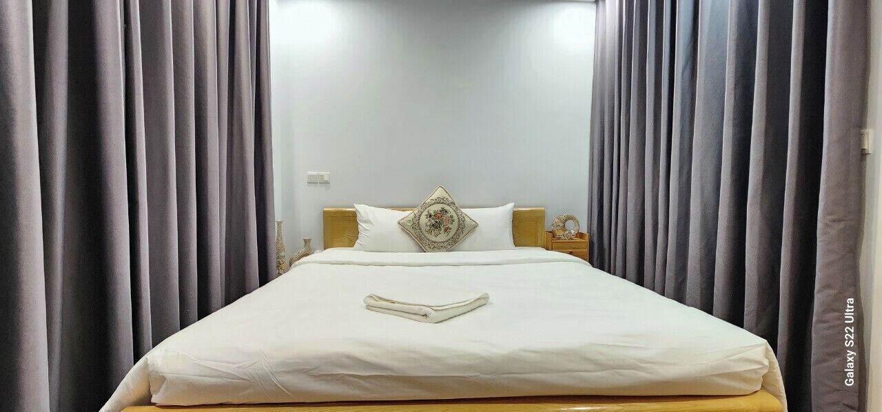 A neatly made bed with a white duvet and pillows, a decorative pillow, and a bedside table with a lamp.