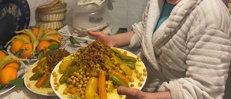 Uma cozinha com bancada de mármore, diversos utensílios e uma pessoa segurando um prato de comida.