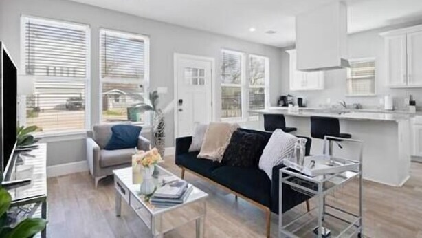 Een moderne woonkamer met een bank, salontafel en een eethoek, met een keuken op de achtergrond.