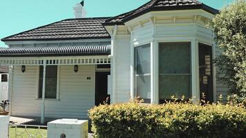A white house with a black roof, a bay window, and a number '15' on the door.