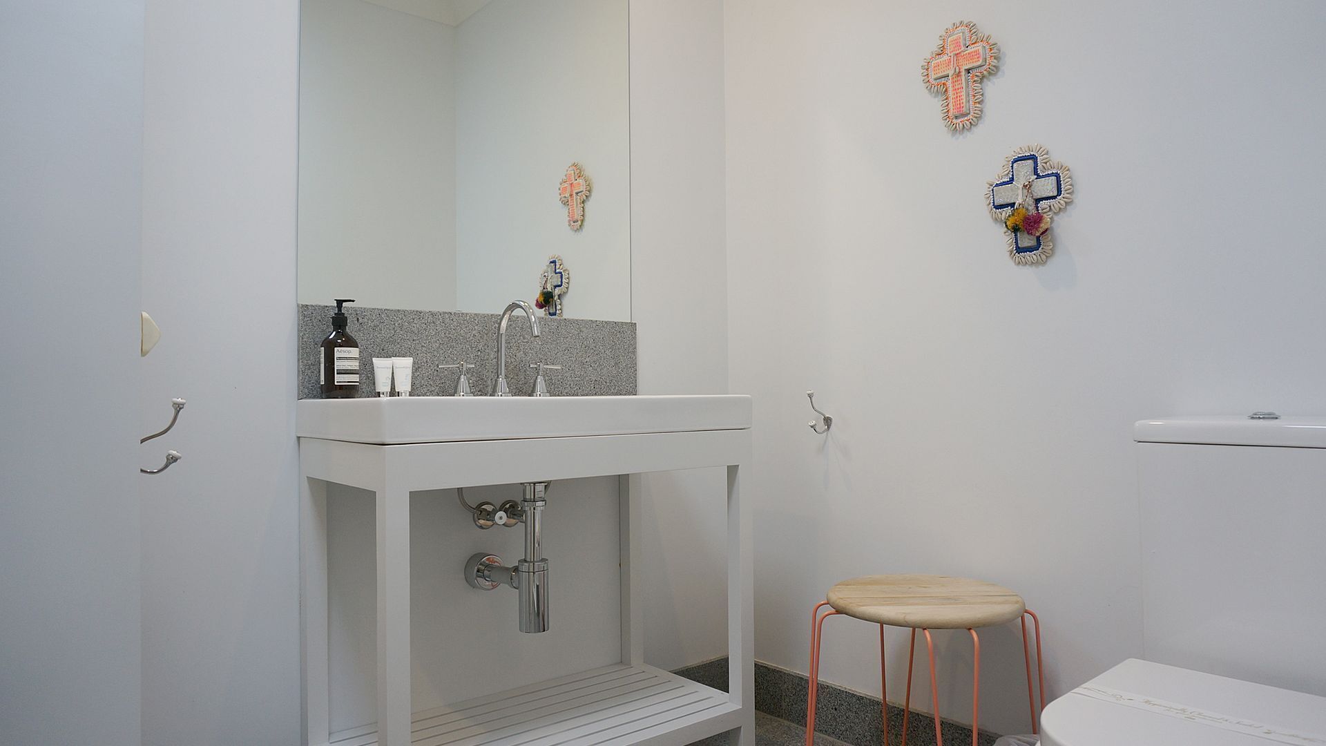 A bathroom with a white sink, mirror, and two wall-mounted cross decorations.
