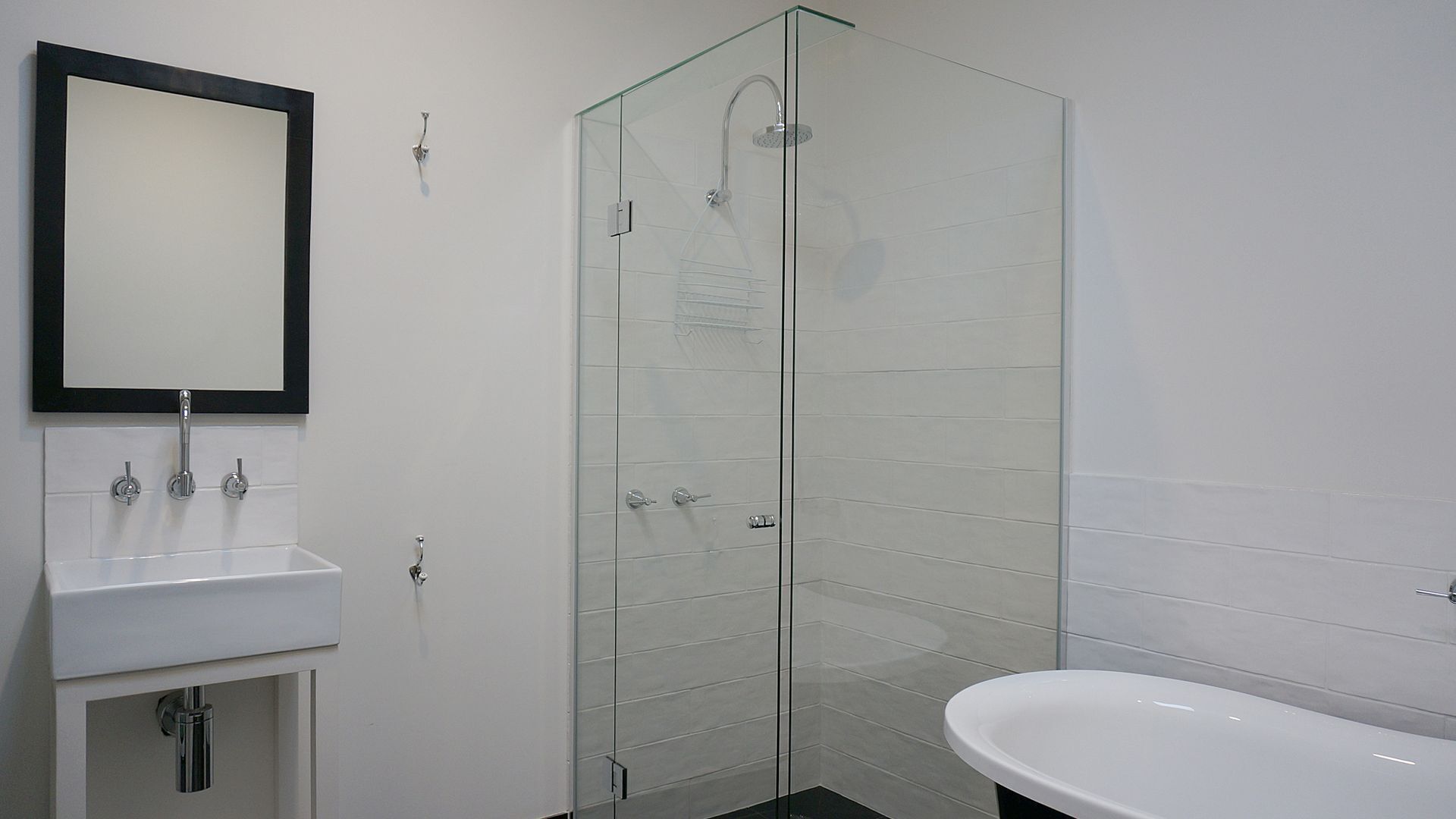 A bathroom with a glass shower enclosure, a white sink, and a mirror.