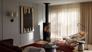 Ein modernes Wohnzimmer mit Kamin, Sofa, Sessel, Couchtisch und Teppich.