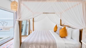 Een slaapkamer met een hemelbed, wit beddengoed en uitzicht op het balkon.