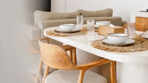 Een moderne eethoek met een ronde tafel, houten stoelen en geweven hanglampen.