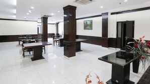 Un vestíbulo amplio con una mesa de recepción, varias mesas y sillas, y una planta decorativa de gran tamaño.