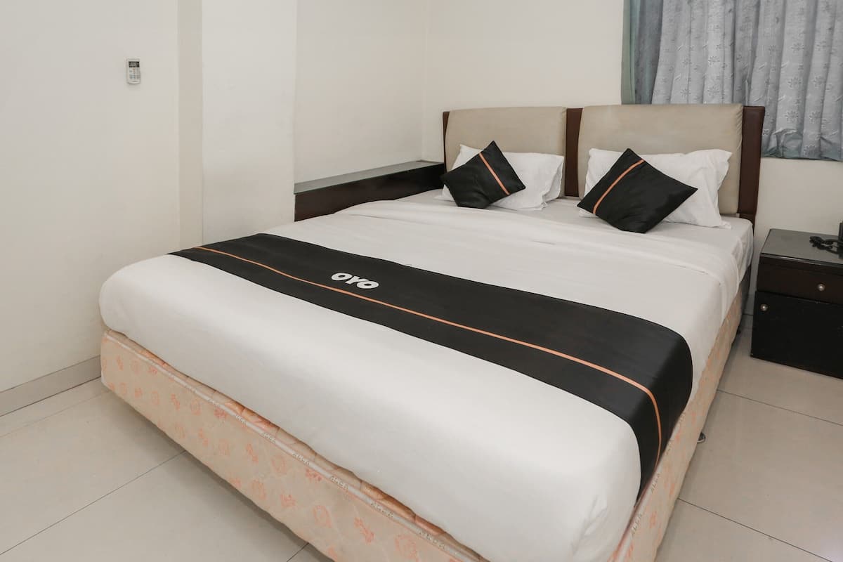 A neatly made bed with a black and white bedspread, a wooden headboard, and a bedside table with a lamp.