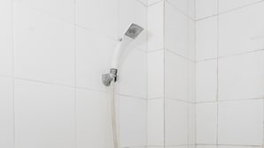 Ducha con cabezal de ducha de mano y grifo empotrado en un baño con azulejos.