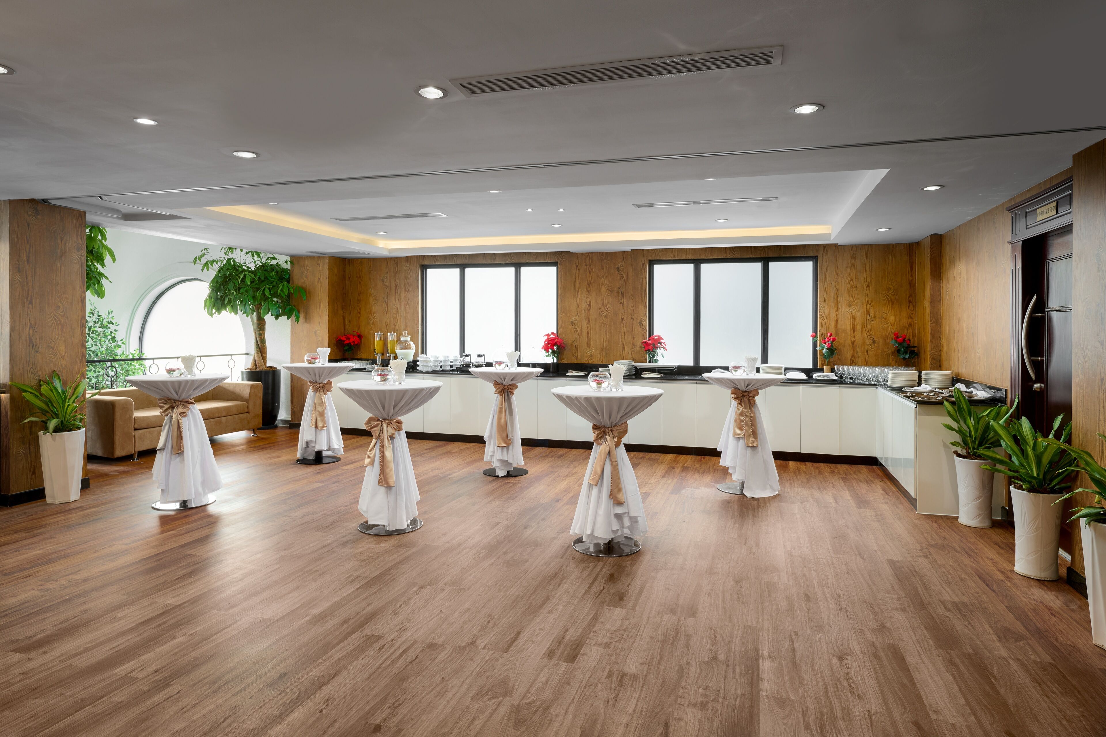 Una cocina moderna con suelo de madera, armarios blancos y mesas redondas con manteles blancos.