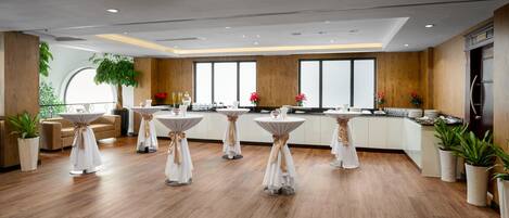 Una cocina moderna con suelo de madera, armarios blancos y mesas redondas con manteles blancos.