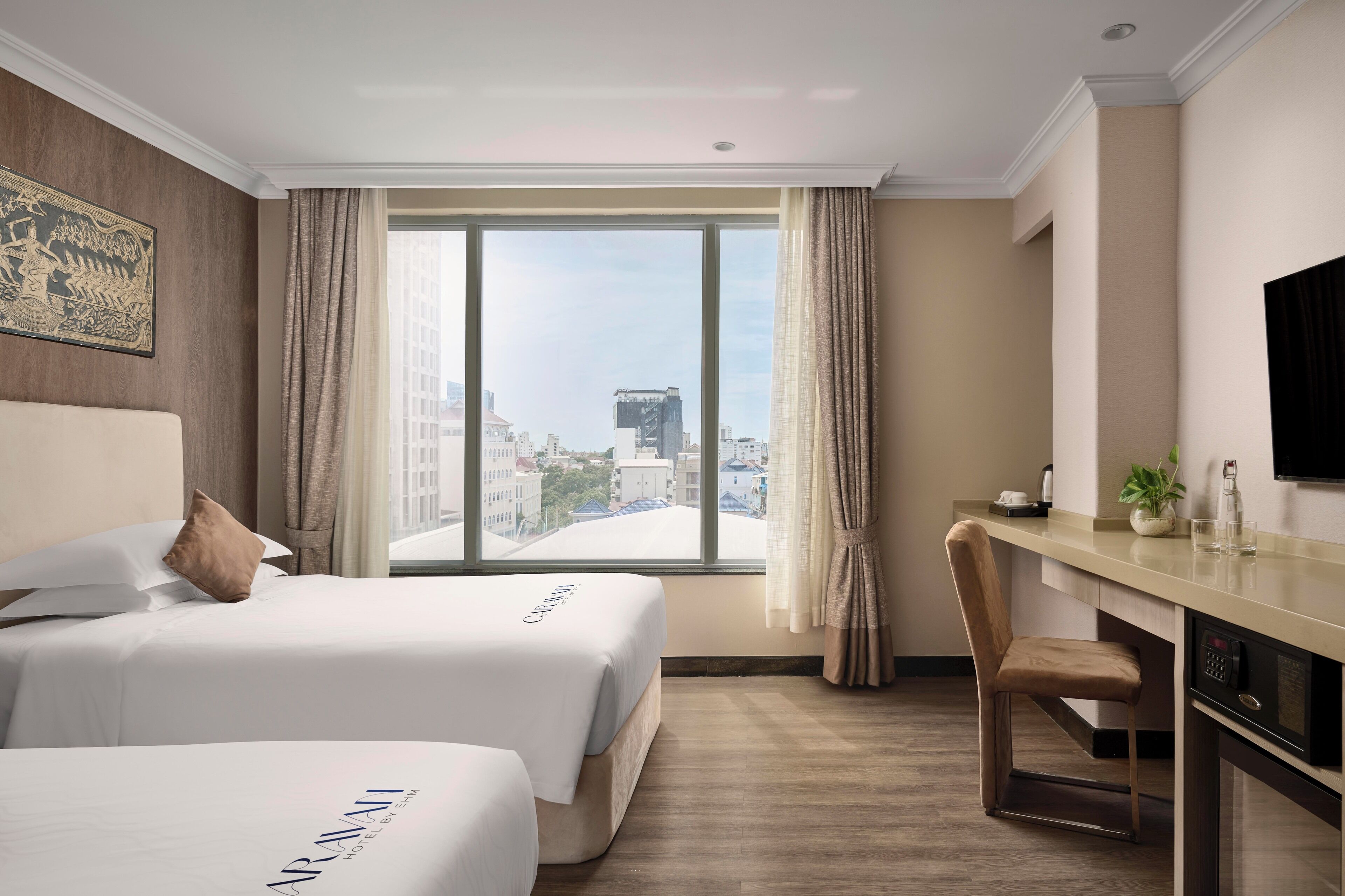 A hotel room with two beds, a desk, a chair, a TV, and a large window with a city view.