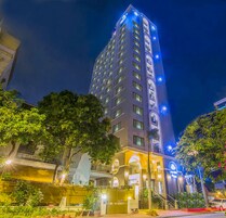 Un hotel de gran altura con varios pisos, una entrada bien iluminada y áreas verdes circundantes con una cerca.