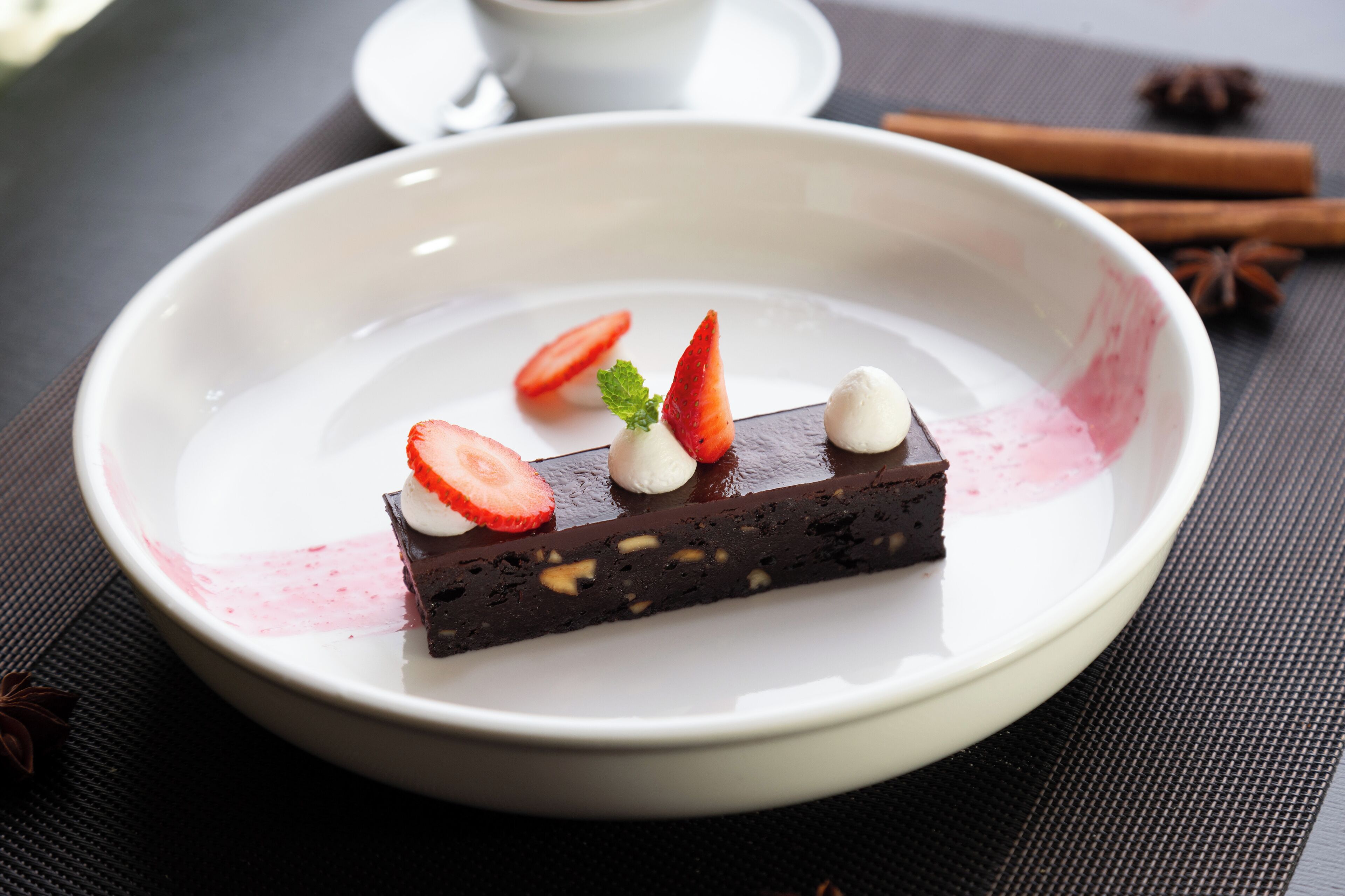 Un postre sobre un plato blanco con fresas y hojas de menta.