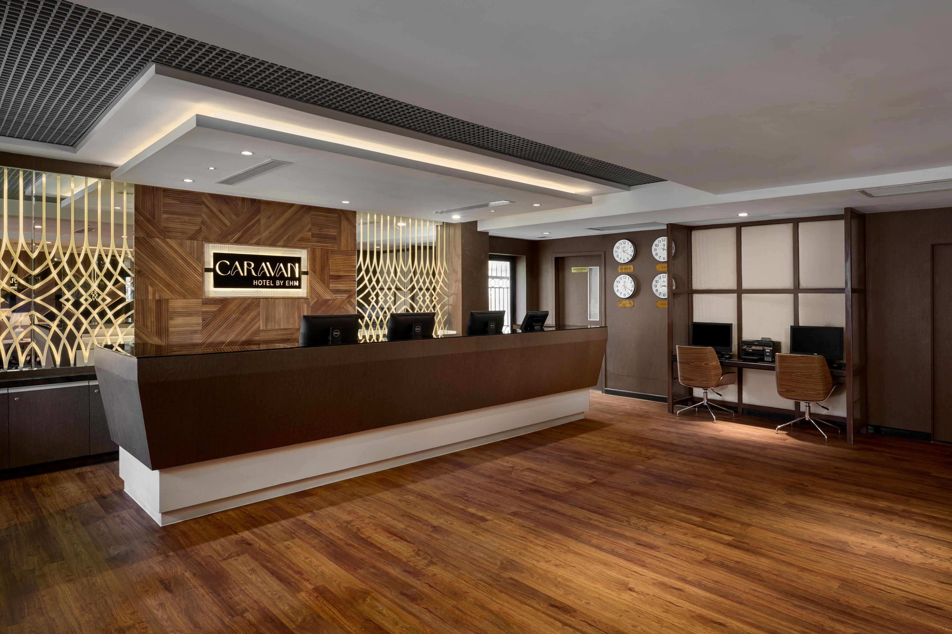 A modern reception desk with a wooden finish and a sign reading "Caravan Hotel by EHM".