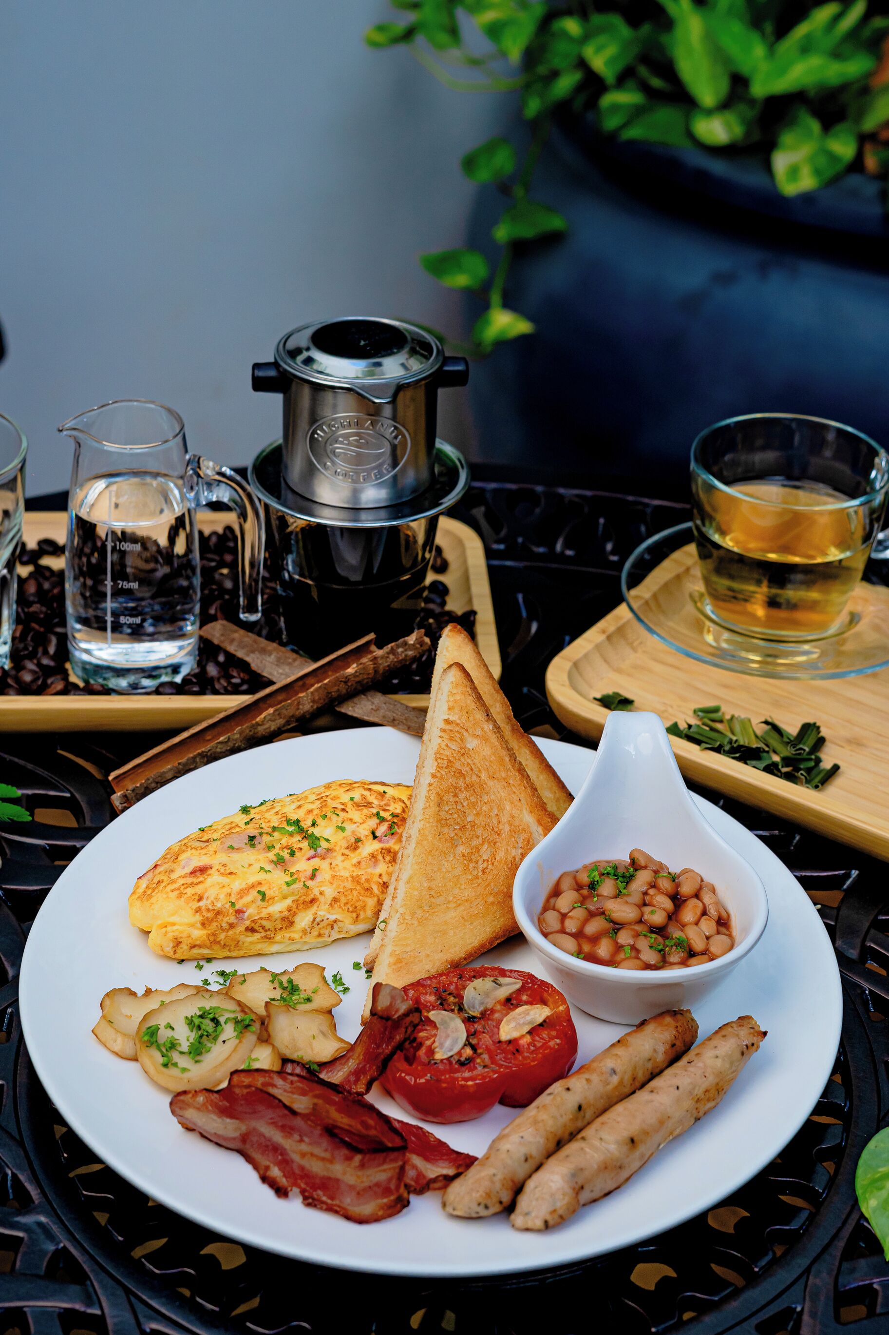Ein Teller mit Frühstück: Toast, Eier, Speck, Würstchen, Bohnen und Tomaten.
