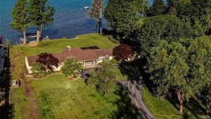 Une maison avec une grande pelouse et vue sur un lac.
