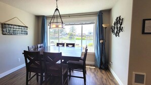 Un espace repas comprenant une table et des chaises, un luminaire suspendu et une vue par la fenêtre.