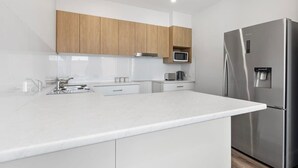 A modern kitchen with white cabinetry, a stainless steel refrigerator, and a microwave.