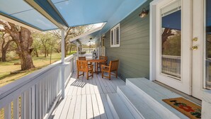 A covered porch with a table and chairs, a door with a window, and a view of the outdoors. - Riverside Texas Retreat w/ Wraparound Porch! (Thorndale)