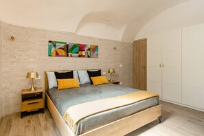 A bedroom with a bed, a nightstand, a lamp, a wall art piece, and a wardrobe.