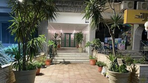 A hotel entrance with a tiled pathway, potted plants, and a staircase leading to the entrance. - One bedroom apartment city views local to Airport (El Nozha)