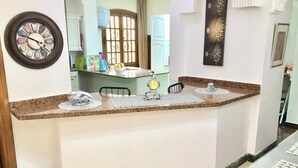 A kitchen with a marble countertop, a clock, and a decorative wall piece. - One bedroom apartment city views local to Airport (El Nozha)