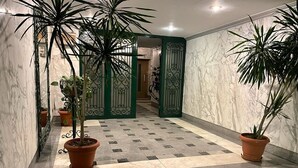 A hallway with a checkered floor, potted plants, and a green gate. - One bedroom apartment city views local to Airport (El Nozha)