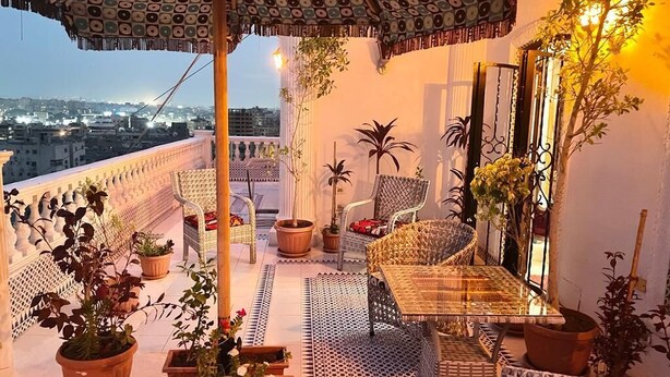 A rooftop terrace with outdoor furniture, potted plants, and a patterned umbrella. - One bedroom apartment city views local to Airport (El Nozha)