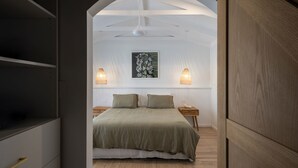 A bedroom with a bed, two bedside tables, a wall-mounted artwork, and two wall-mounted lamps. - Pool - Ohana - Oceanstays (Yamba)