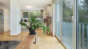 Una cocina moderna con un ventanal grande, un comedor con un banco y una planta en maceta.