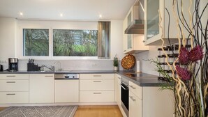 Una cocina moderna con un amplio ventanal, electrodomésticos integrados y un arreglo decorativo de plantas.