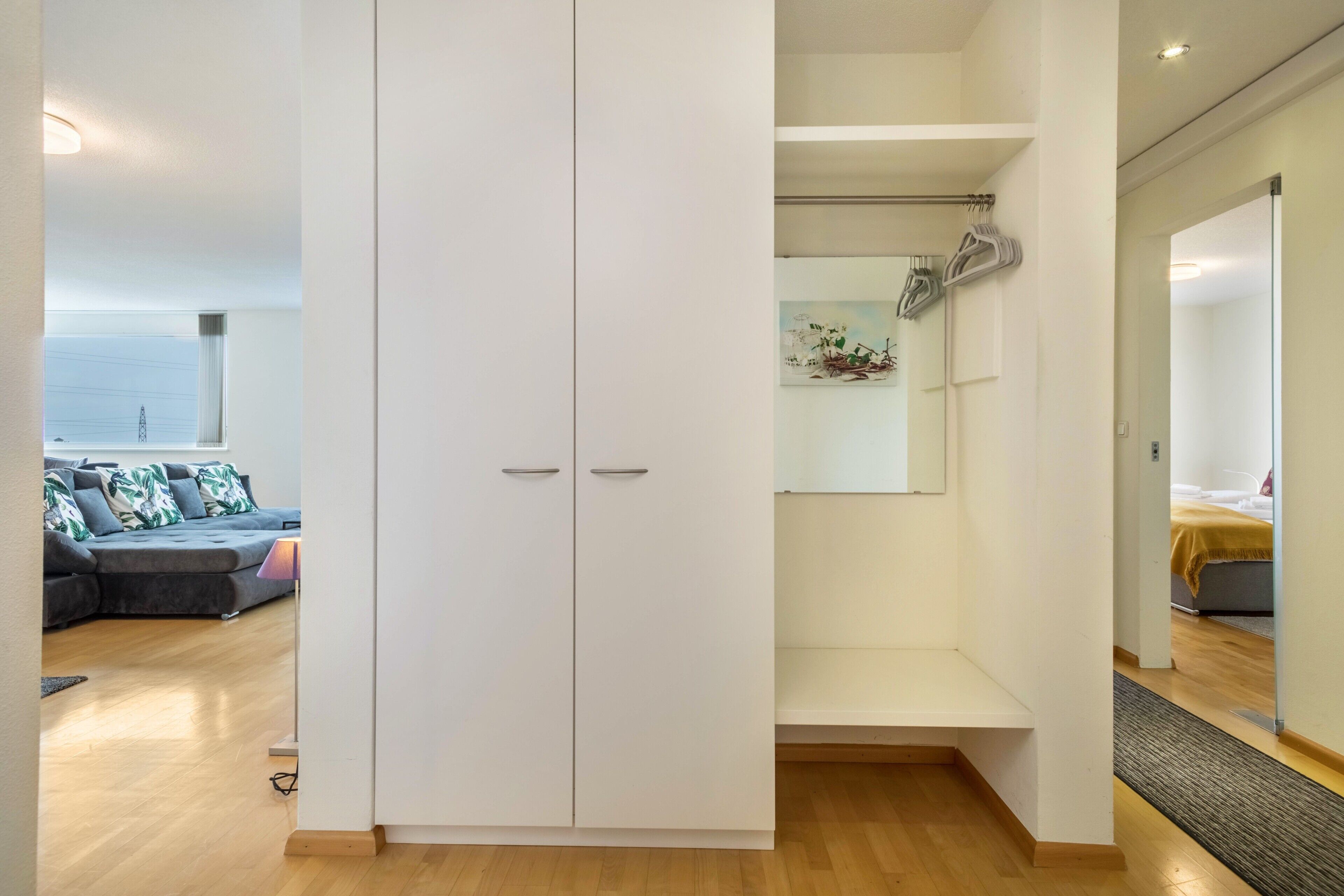 A modern room with a white wardrobe, a sofa, and a view of the city.
