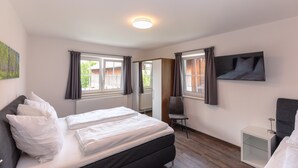 Une chambre d’hôtel avec un lit, une chaise, une télévision et une fenêtre.