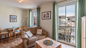 Ein gemütliches Wohnzimmer mit Ledersofa, Holztisch und einem Essbereich mit Tisch und Stühlen.