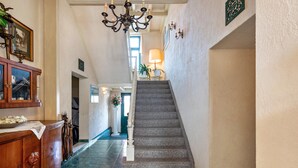 Eine prächtige Treppe mit einer Chandelüster, einem Holzschrank und einem Blumentopf.