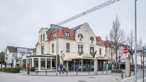 Ein Gebäude mit Café und Restaurant im Erdgeschoss, einer Fußgängerampel und einem Verbotsschild für Fahrzeuge.