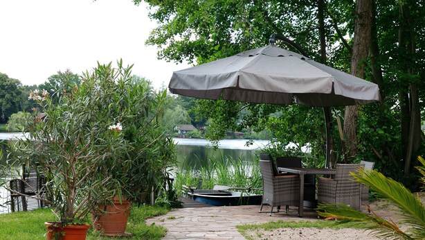 A stone pathway leading to outdoor furniture and a boat by a lake. - Lakefront Holiday Cottage with Private Terrace and Wi-Fi (Bestensee)