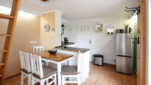 A compact kitchen with a wooden table and chairs, a built-in island, a stainless steel refrigerator, and a trash bin. - Lakefront Holiday Cottage with Private Terrace and Wi-Fi (Bestensee)