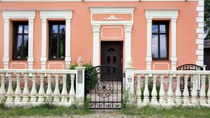 A building with a symmetrical facade, a central entrance with a decorative arch, and a gated driveway. - Lakefront Holiday Cottage with Private Terrace and Wi-Fi (Bestensee)