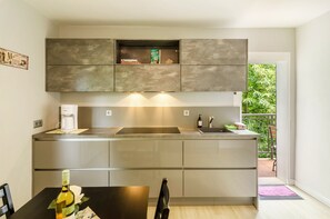 A modern kitchen with built-in cabinets, a coffee maker, and a dining area with a table and chairs. - Apartment 'Fewo2 Seelter Uutkiek Saterland' with Private Terrace, Shared Garden and Wi-Fi (Saterland)