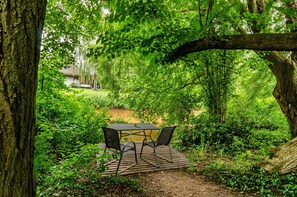 A wooden deck with a table and chairs surrounded by lush greenery and trees. - Apartment 'Fewo2 Seelter Uutkiek Saterland' with Private Terrace, Shared Garden and Wi-Fi (Saterland)