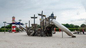 Ein Spielplatz mit Rutsche, Klettergerüsten und einer turmartigen Konstruktion.