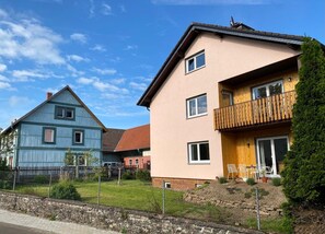 A residential area with houses, a wooden fence, and a stone wall. - Ferienhof im Salzbachtal ­ –  Wildbiene Plus für bis zu sechs Personen (Freiensteinau)