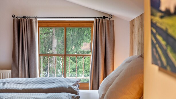 Une chambre avec une grande fenêtre, un lit avec des oreillers et une tringle à rideaux.