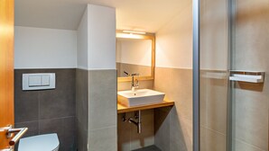 Une salle de bain moderne équipée de toilettes, d’un lavabo et d’une douche.