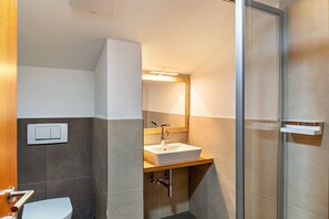 A modern bathroom with a toilet, sink, and shower.
